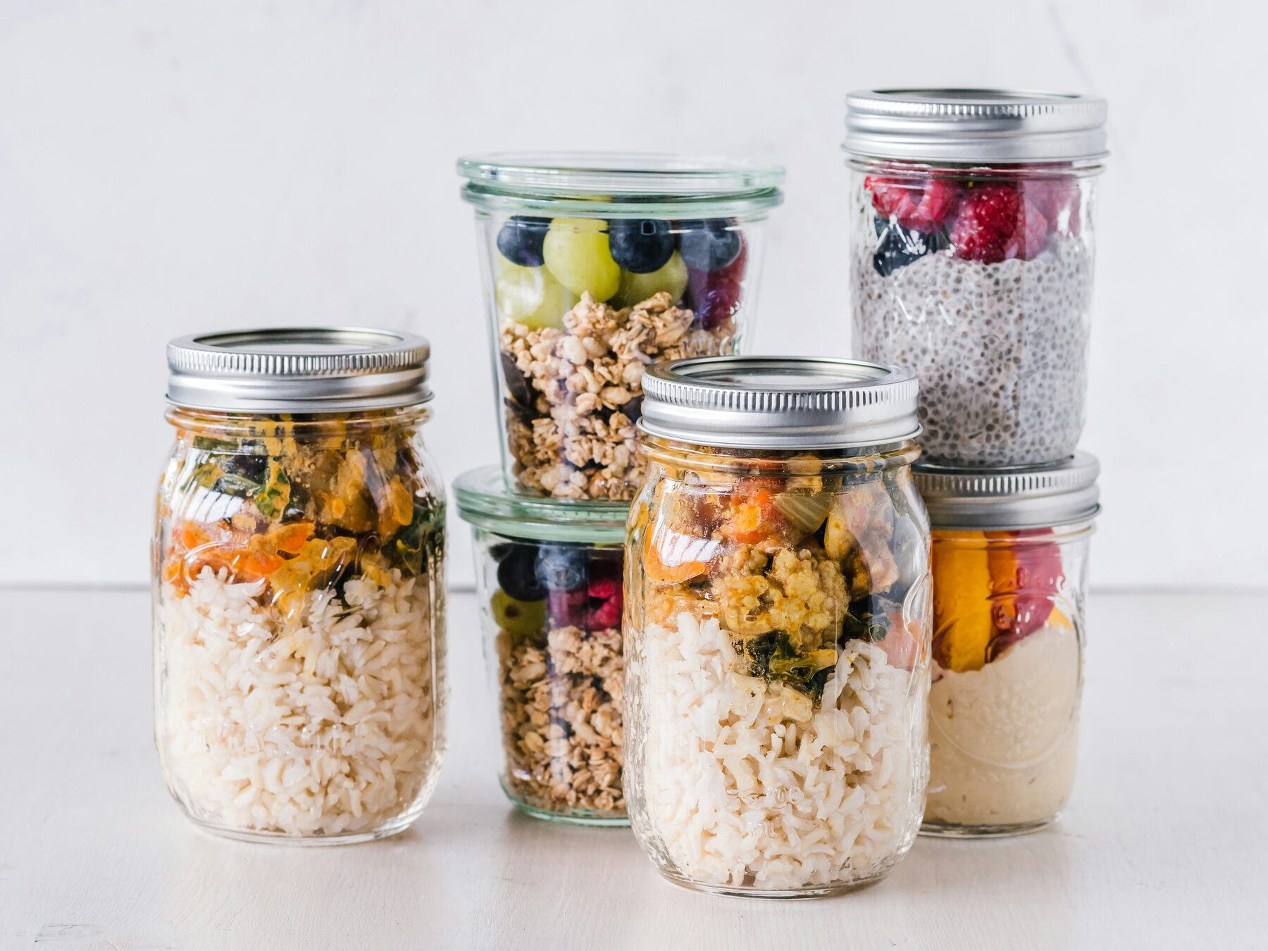 Mason jars of grains, fruit and seeds lined up on a counter