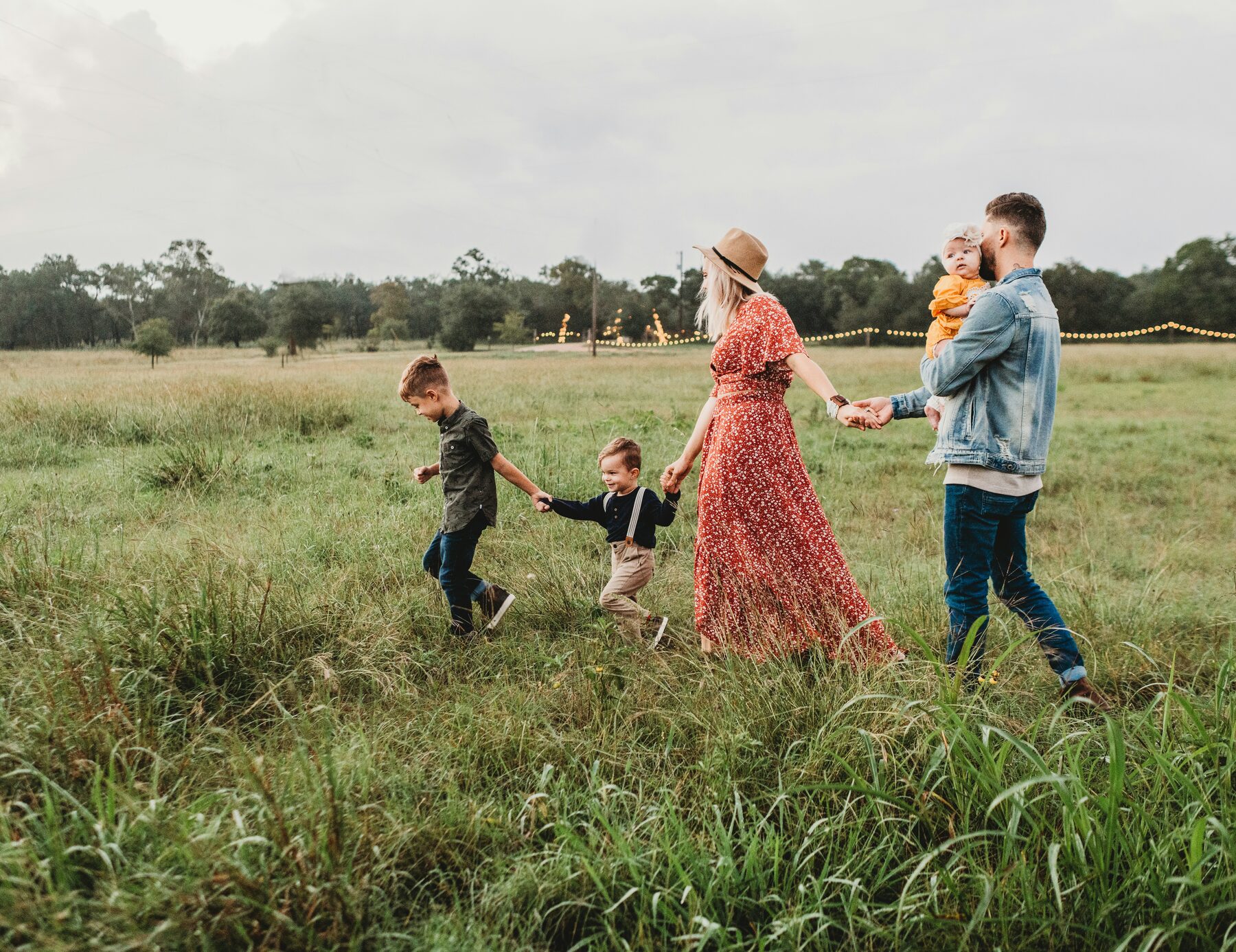 A family running together through a golden North Carolina field at sunset